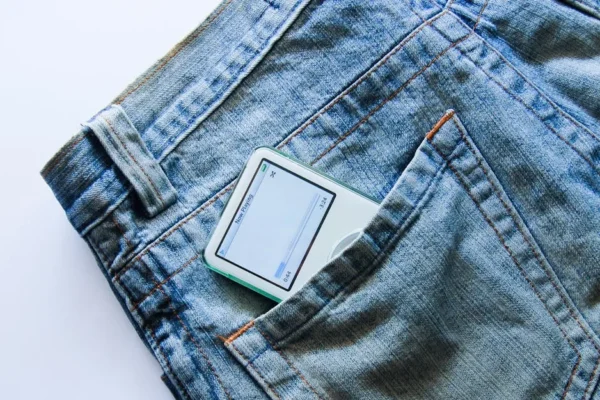 Close-up of a vintage MP3 player partially visible in a denim jeans pocket.