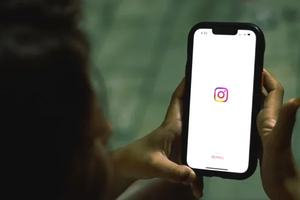 Close-up of a woman holding a smartphone displaying the Instagram app indoors.